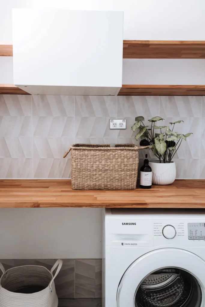 A front-loading washing machine beneath a wooden laundry counter.