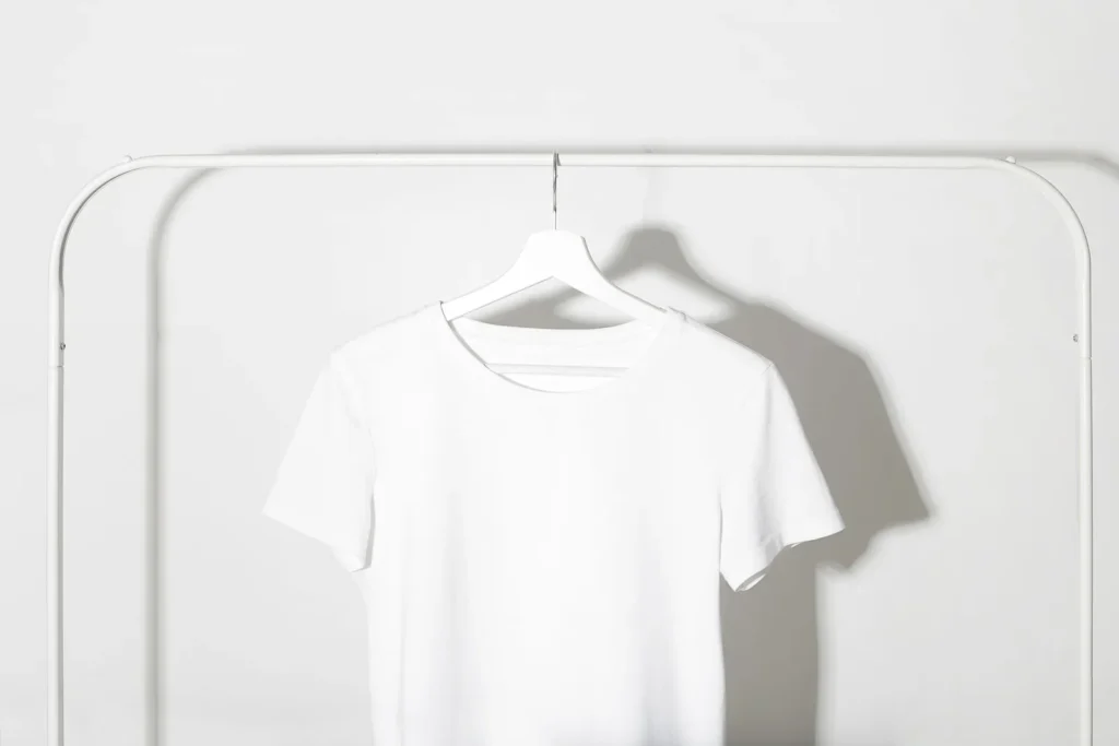 White short-sleeve T-shirt hanging on a white clothing rack.