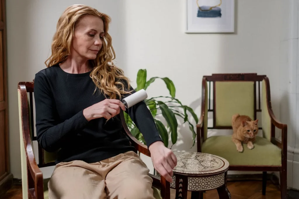 Woman using a lint roller on the sleeve of a dark top.