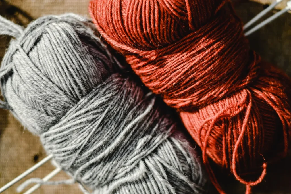 Close-up of gray and rust-colored yarn balls with knitting needles.