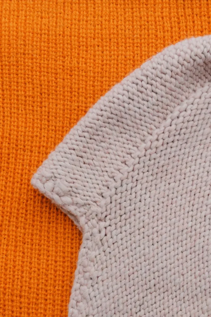 Orange and pale knitted fabrics showing different stitch textures.