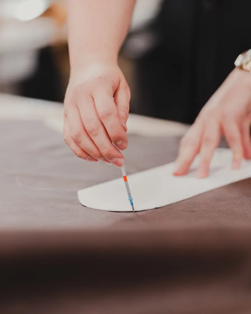 Hands tracing a garment pattern onto fabric with a pencil