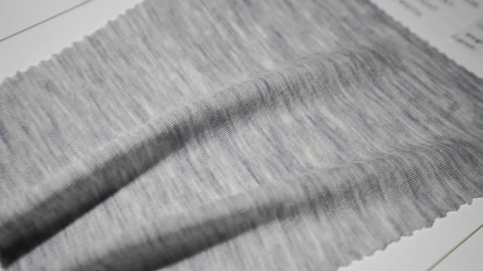 Close-up of light grey merino wool blend fabric showing its knitted texture and natural drape.