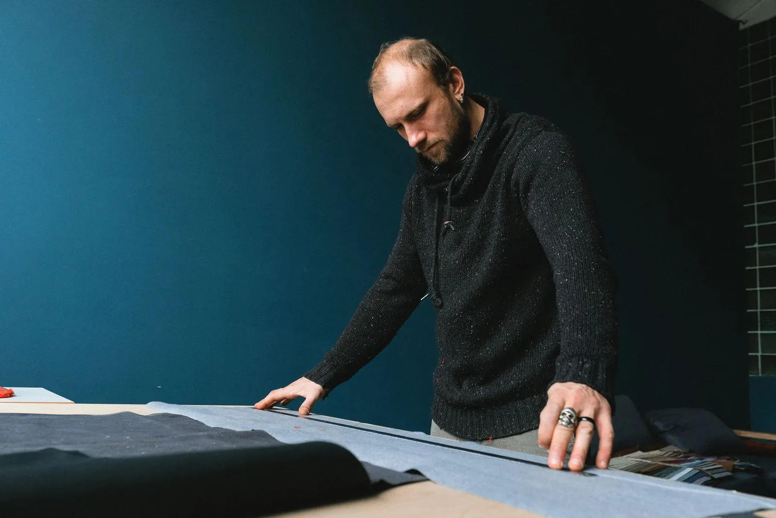 Tailor measuring fabric on a worktable during garment development