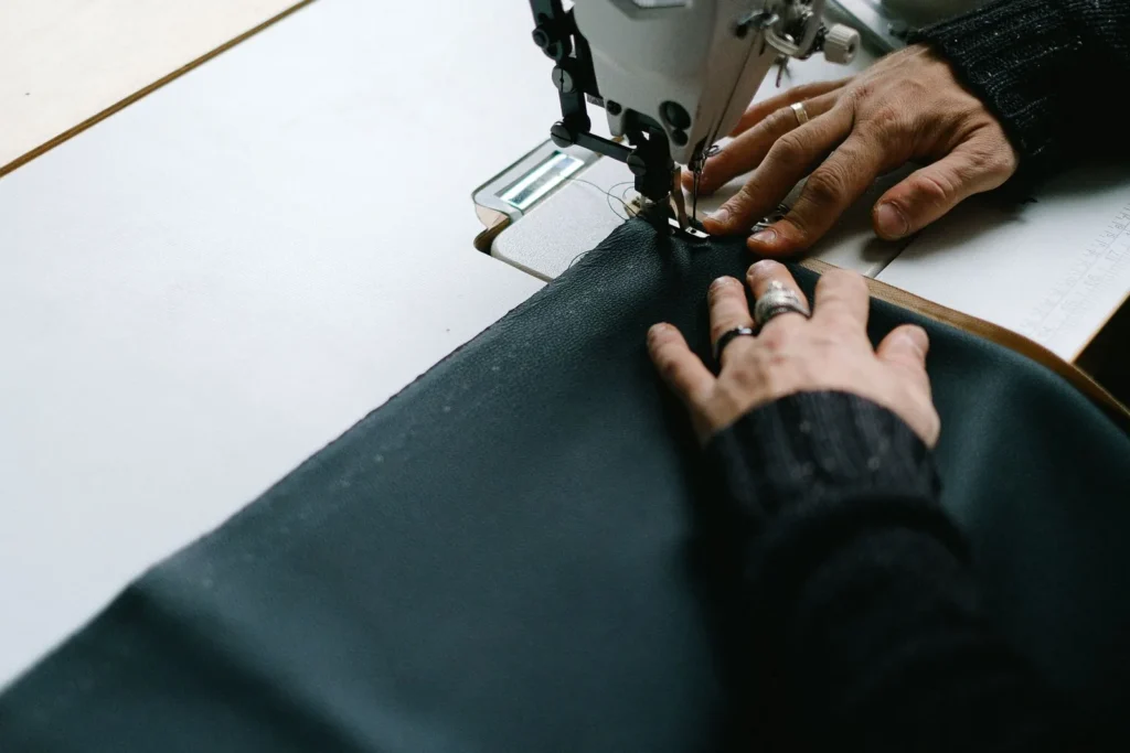 Hands guiding dark fabric through a sewing machine